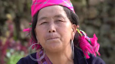 Sapa, Vietnam - Mart 06, 2020: Geleneksel kıyafet ve mücevher giyen etnik Hmong kadını turistlerin Sapa, Kuzey Vietnam 'daki dağ köyünde el sanatları satmalarını bekliyor