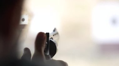 Adam atış poligonundaki hedeflere tabancayla ateş ediyor. Yaklaş, bulanık odaklan. Atış talimi yaparken arkadan ateş eden bir adamın görüntüsü. Yavaş çekim