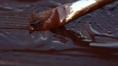 Sanatçı bir yüzeyi fırça kullanarak, yakın plan, yenileme ve yaratıcılık kavramı kullanarak kahverengi boyayla boyuyor.