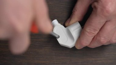 Phillips tornavida kullanarak beyaz elektrik prizinin vidasını gevşet ve kapat. Plastik elektrik prizinin gövdesini ayrıştırma işlemi. Elektrik ekipmanlarının onarımı ve bakımı