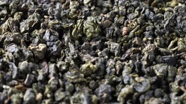 Süt aromalı yeşil çay yapraklı oolong. Yaklaş. Kurumuş yeşil çay yapraklarının arka planı, dönüşler, makro
