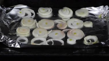 Aşçı limon dilimli sazan balığını fırında pişirmek için soğan ve fırında pişirme tepsisine koyar.