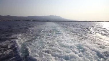 Hızlı yat teknesiyle mavi okyanus suyu dalgası pervane yıkama köpüğünü uyandırıyor. Geminin hareketi sırasında su damlaları sıçrıyor. Seyahat ve doğa kavramı