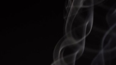 Siyah arka planda beyaz duman yavaş çekimde. Beyaz buhar döner ve yükselir.