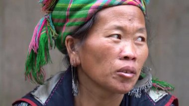 Sapa, Vietnam - Mart 06, 2020: Geleneksel kıyafet ve mücevher giyen etnik Hmong kadını turistlerin Sapa, Kuzey Vietnam 'daki dağ köyünde el sanatları satmalarını bekliyor