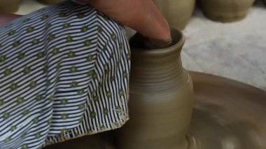 Bir kadın çömlekçinin yakın plan çekimi ayağıyla bir tekerleği döndürür ve eski şehir Hoi An, Vietnam 'da çömlek imalatında elleriyle güzel bir çömlek yapar.