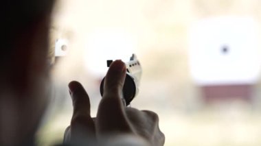 Adam atış poligonundaki hedeflere tabancayla ateş ediyor. Yaklaş, bulanık odaklan. Atış talimi yaparken arkadan ateş eden bir adamın görüntüsü. Yavaş çekim