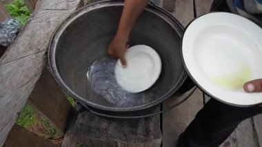 Ukraynalı erkek çiftçi çiftlik bahçesinde bulaşıkları temiz suyla yıkıyor, kapalı, açık havada. Kırsal gelenekler. Batı Ukrayna