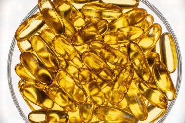 Omega 3 'lü balık yağı kapsülleri ve beyaz arka planda cam D vitamini, yakın plan, üst manzara. Jelatin kapsüllerde altın balık yağı