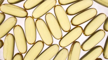 Omega 3 ve beyaz arka planda D vitamini içeren balık yağı kapsülleri, yakın plan, dönüyor. Jelatin kapsüllerde altın balık yağı