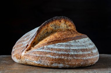 Tahta kesme tahtasının üzerinde taze pişmiş ekşi ekmeğin yuvarlak somunu, yakın çekim. Rustik ekşi ekmek. Evde sağlıklı ekşi ekmek pişirmek.