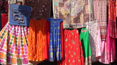 Udaipur, Rajasthan, Hindistan 'daki yerel sokak pazarında satılık renkli kıyafetlerin çeşitli ürünleri. Kapat.