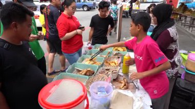 Kota Kinabalu, Malezya - 18 Şubat 2020: Malezyalı çocuk Malezya 'nın Borneo Adası' ndaki Kota Kinabalu kentindeki gece sokak gıda pazarında kızarmış muz ve hamur işi satıyor