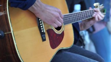 Sokakta oturup gitar çalmaya çalışan genç adam elleri. Hobi konsepti. Adam gitar çalıyor. Parmaklar ve ipler kapansın