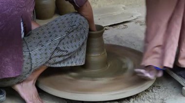 Close-up of a woman potters rotate a wheel with her foot and making a beautiful clay pot with her hands at pottery manufacture in the Old Town Hoi An, Vietnam