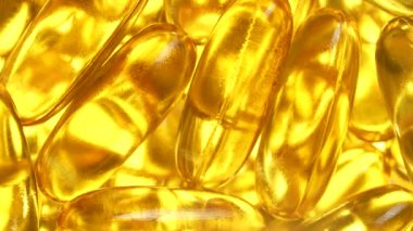 Omega 3 ve beyaz arka planda D vitamini içeren balık yağı kapsülleri, yakın plan, dönüyor. Jelatin kapsüllerde altın balık yağı