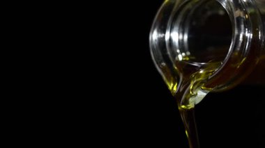 Ekstra saf zeytinyağı siyah arka planda temiz bir cam şişeden dökülüyor, yaklaşın, yavaş çekimde. Organik sıvı akışı, kopyalama alanı