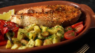Kırmızı biberli, patatesli, domatesli ve limonlu lezzetli somon balığı. Masadaki kil tabakta, kapat, döndür.