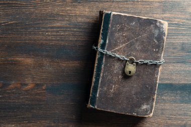 Metal zincir ve asma kilit, ahşap arka plandaki eski kitap, yakın plan, üst manzara. Metin için alanı kopyala
