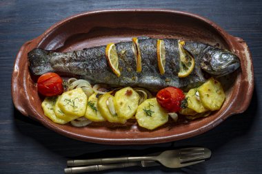 Kil tabakta patates dilimli, limonlu, domatesli ve baharatlı alabalık.