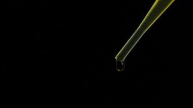 Siyah arka planda gerekli yağ damlalarıyla kozmetik pipeti, makro görünüm. Doğal kozmetik veya ilaç kavramı