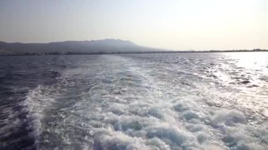 Hızlı yat teknesiyle mavi okyanus suyu dalgası pervane yıkama köpüğünü uyandırıyor. Geminin hareketi sırasında su damlaları sıçrıyor. Seyahat ve doğa kavramı