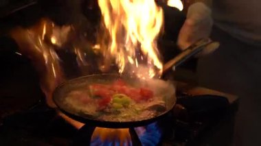 Şef, sebzeleri kızartıp tavaya atıyor. Türkiye 'deki sokak kafesinde sebzeli kızartma tavalarının büyük bir alevle kavruluşunun yavaş çekim görüntüsü. Mutfakta kızarmış sebze pişireceğim.