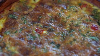 Ceramic bowl with vegetable frittata, simple vegetarian food. Frittata with tomato, pepper, onion and cheese on wooden table, close up. Italian egg omelette, rotates