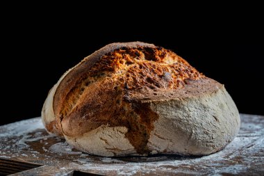 Tahta kesme tahtasının üzerinde taze pişmiş ekşi ekmeğin yuvarlak somunu, yakın çekim. Rustik ekşi ekmek. Evde sağlıklı ekşi ekmek pişirmek.