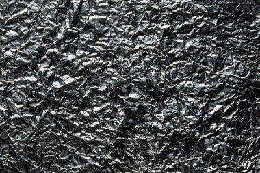 Buruşuk çikolata folyosunun arka planı ve dokusu, yakın plan, üst manzara. Çikolata şekersiz parlak alüminyum folyo.