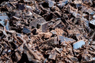 Arka planda kırılmış siyah çikolata yığını, yakın çekim. Tatlı yemek.