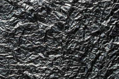 Buruşuk çikolata folyosunun arka planı ve dokusu, yakın plan, üst manzara. Çikolata şekersiz parlak alüminyum folyo.