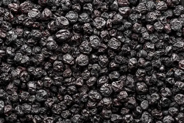 Kurutulmuş yaban mersini arka planı, yakın plan, üst manzara, makro. Kurutucudan bir yığın kuru yaban mersini. Kış için vitamin ve sağlıklı beslenme kavramı