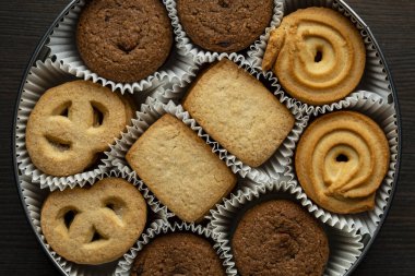 Tahta masada yuvarlak metal bir kutuda çıtır çıtır kurabiyeler, üst manzara, kapat.