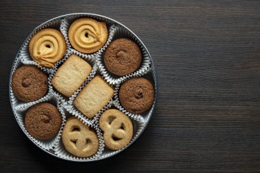 Tahta masadaki yuvarlak metal bir kutuda çıtır çıtır kurabiye, üst manzara, kapat, kopyala