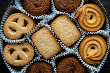 Tahta masada yuvarlak metal bir kutuda çıtır çıtır kurabiyeler, üst manzara, kapat.