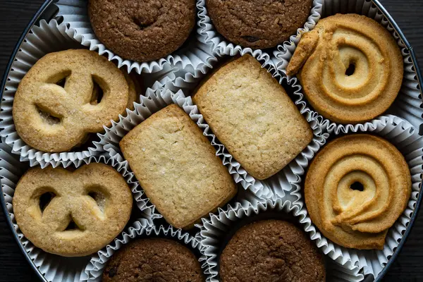 Tahta masada yuvarlak metal bir kutuda çıtır çıtır kurabiyeler, üst manzara, kapat.