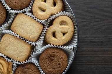 Tahta masadaki yuvarlak metal bir kutuda çıtır çıtır kurabiye, üst manzara, kapat, kopyala
