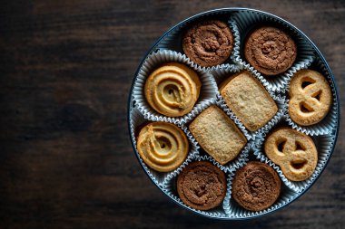 Tahta masadaki yuvarlak metal bir kutuda çıtır çıtır kurabiye, üst manzara, kapat, kopyala