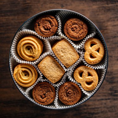 Tahta masada yuvarlak metal bir kutuda çıtır çıtır kurabiyeler, üst manzara, kapat.