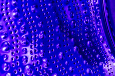 İçerideki mavi ışıkta boş çamaşır makinesi varili, görüntüyü kapat. Soyutlama ve arkaplan olarak metal noktalar ve kabarcıklar