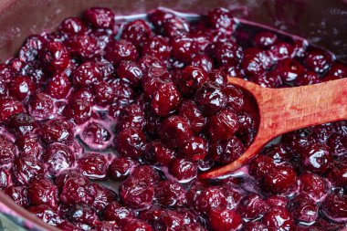 Tahta kaşıkla kiraz reçeli yapmak için taze toplanmış kirazlı şekeri hazırlıyorum. Çilek reçeli, ev yemeği.