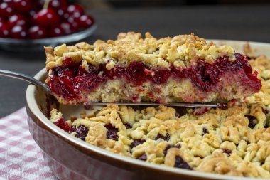 Lezzetli vişneli turtayla pişirme tabağı, yakın çekim. Tahta masada taze kırmızı kirazlı nefis ev yapımı turta. Böğürtlenli kısa hamurlu turta