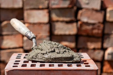 Çimento karışımı ya da harç. İnşaat alanındaki kırmızı tuğlada çimento tozu ve mala yakın.