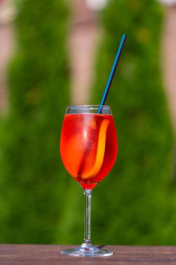 Aperol spritz kokteyli ve şarap kadehi, doğal bir arka plan. Klasik İtalyan aperatifi aperatif sprey kokteyli. Bir dilim portakallı. Kapatın. Yaz güneşli ferahlatıcı içecek