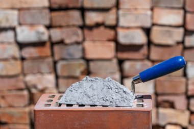 Kuru çimento ya da harç. İnşaat alanındaki kırmızı tuğlada çimento tozu ve mala yakın.