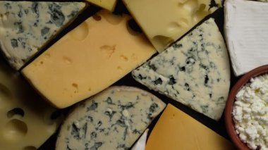 Siyah arkaplanda farklı peynirler, yakın plan, üst görünüm. Çeşitli peynir türleri