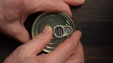 Erkek el, ahşap bir masada kırmızı havyar konservesini açıyor, yakın plan, üst manzara. Somon havyarı.