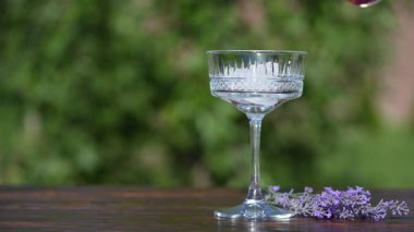 Parlak yaz kokteyli ya da kristal bardakta limonata ile ahşap masanın arka planında, yakın plan. Lavanta çiçekleri ile iç. Güneşli bir günde rahatlamak için lezzetli bir alkollü içecek.