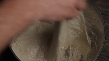 Erkek fırıncı elleriyle ekmek pişirmek için mayasız hamur uzatıyor, yakın plan, üst görüş